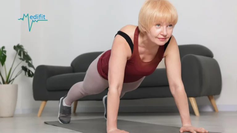 Une physiothérapeute de Medifit aide une patiente âgée souriante à réaliser des pompes lors d'une séance de rééducation personnalisée à domicile.