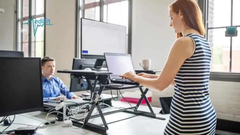 Femme utilisant un bureau assis-debout ergonomique en entreprise pour une meilleure prévention du mal de dos au bureau